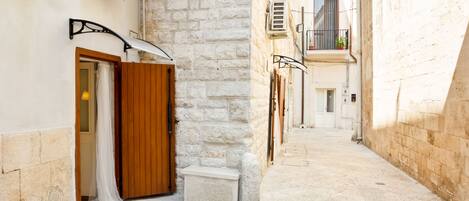 A narrow alleyway with a stone wall on one side and a wooden door on the other.