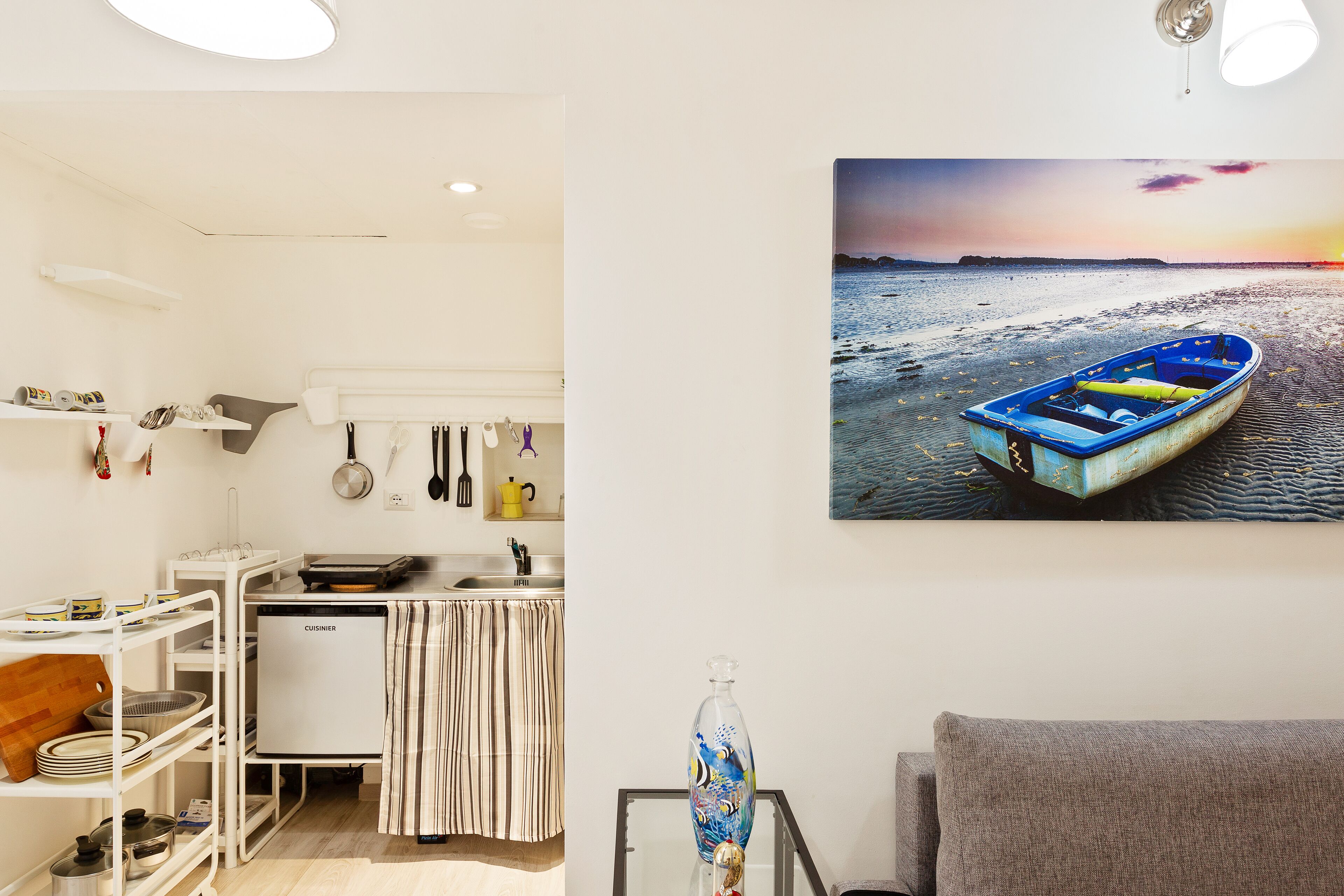 A compact kitchen with a fridge, a dining area, and a wall-mounted rack.