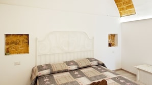 A bedroom with a white bed, patterned bedding, and a brick archway. - San Nicola Casa Clemente Apartment (Bari)