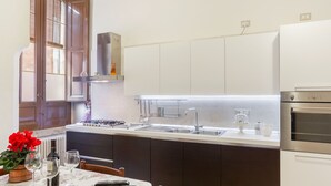 A compact kitchen with a central island, a built-in oven, and a window with blinds. - La terrazza sulla Chiesa di San Francesco d'Assisi (Castellana Grotte)