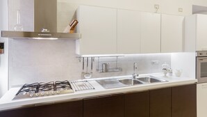 A modern kitchen with white cabinets, stainless steel appliances, and a built-in oven. - La terrazza sulla Chiesa di San Francesco d'Assisi (Castellana Grotte)