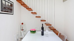 A modern interior with a white table, a bottle of wine, and a glass. A staircase with wooden steps and metal railings is visible. - Cute flat in the heart of Monopoli (Monopoli)