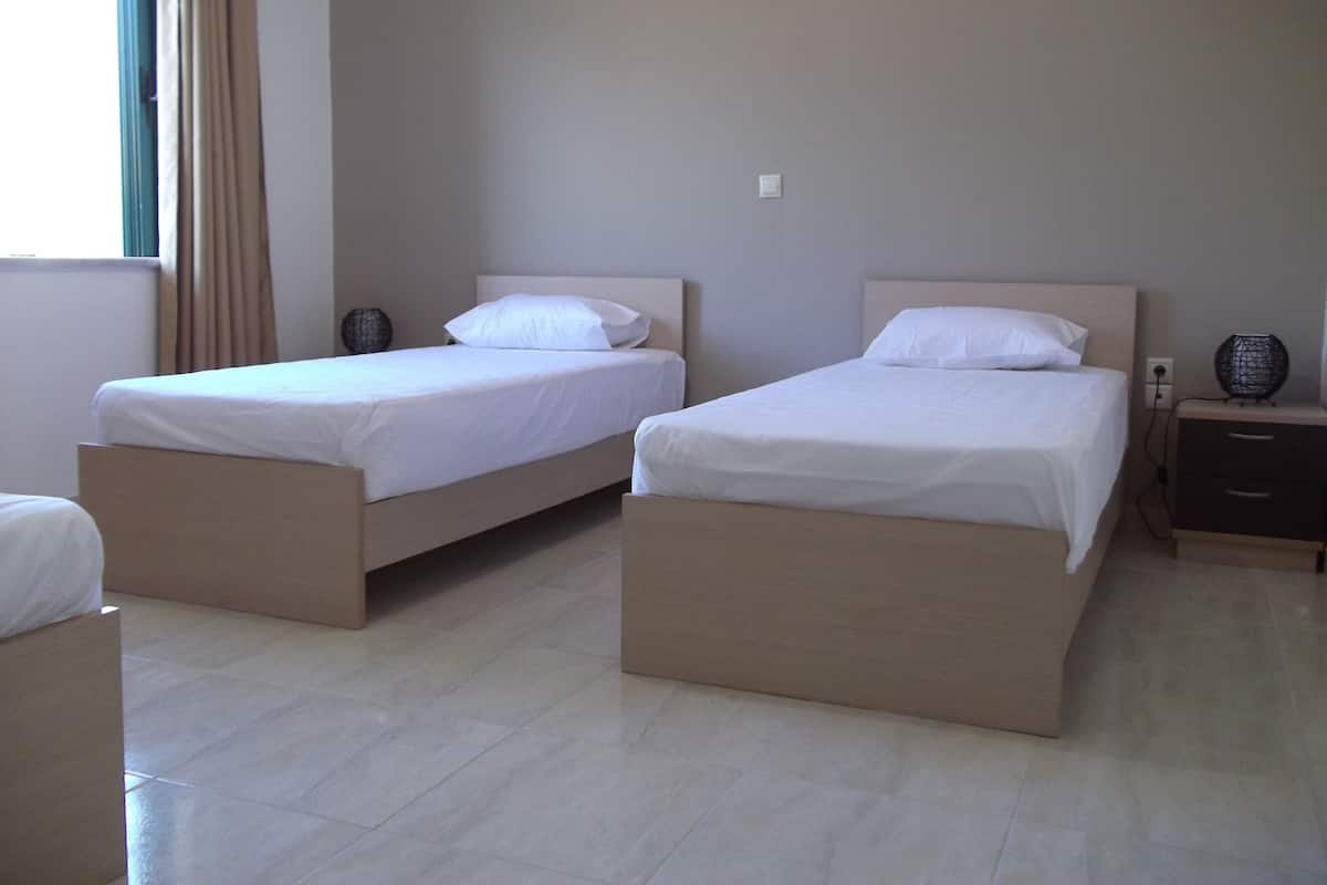 Two single beds with wooden frames and white bedding in a hotel room.