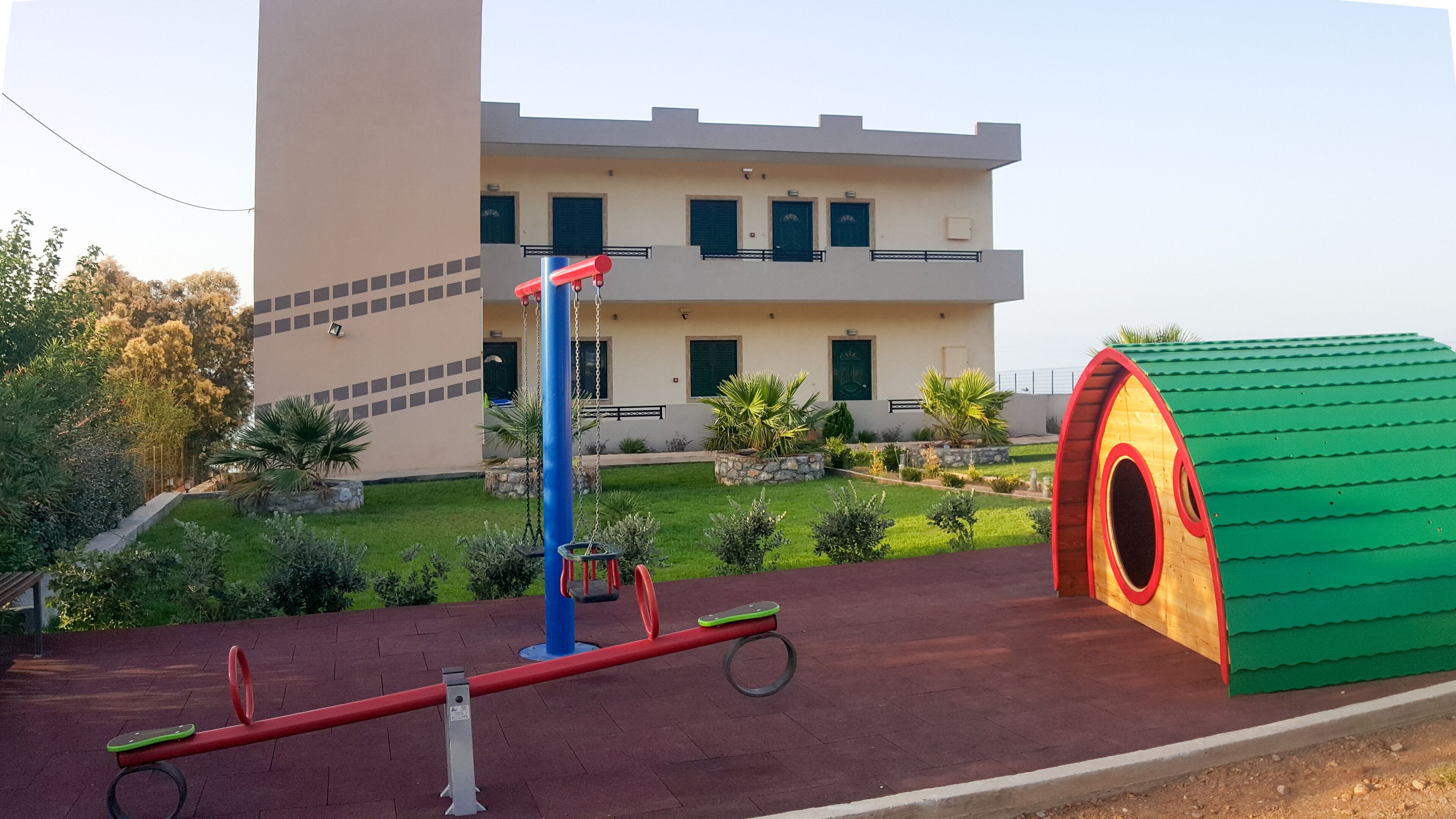 A playground with seesaws and a green tunnel structure.
