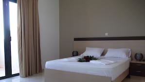Habitación de hotel con una cama grande, una mesita de noche, una lámpara y vistas al exterior.