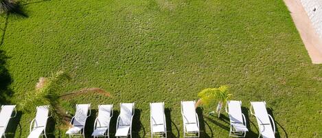 An aerial view of a grassy area with white lounge chairs arranged in a row.