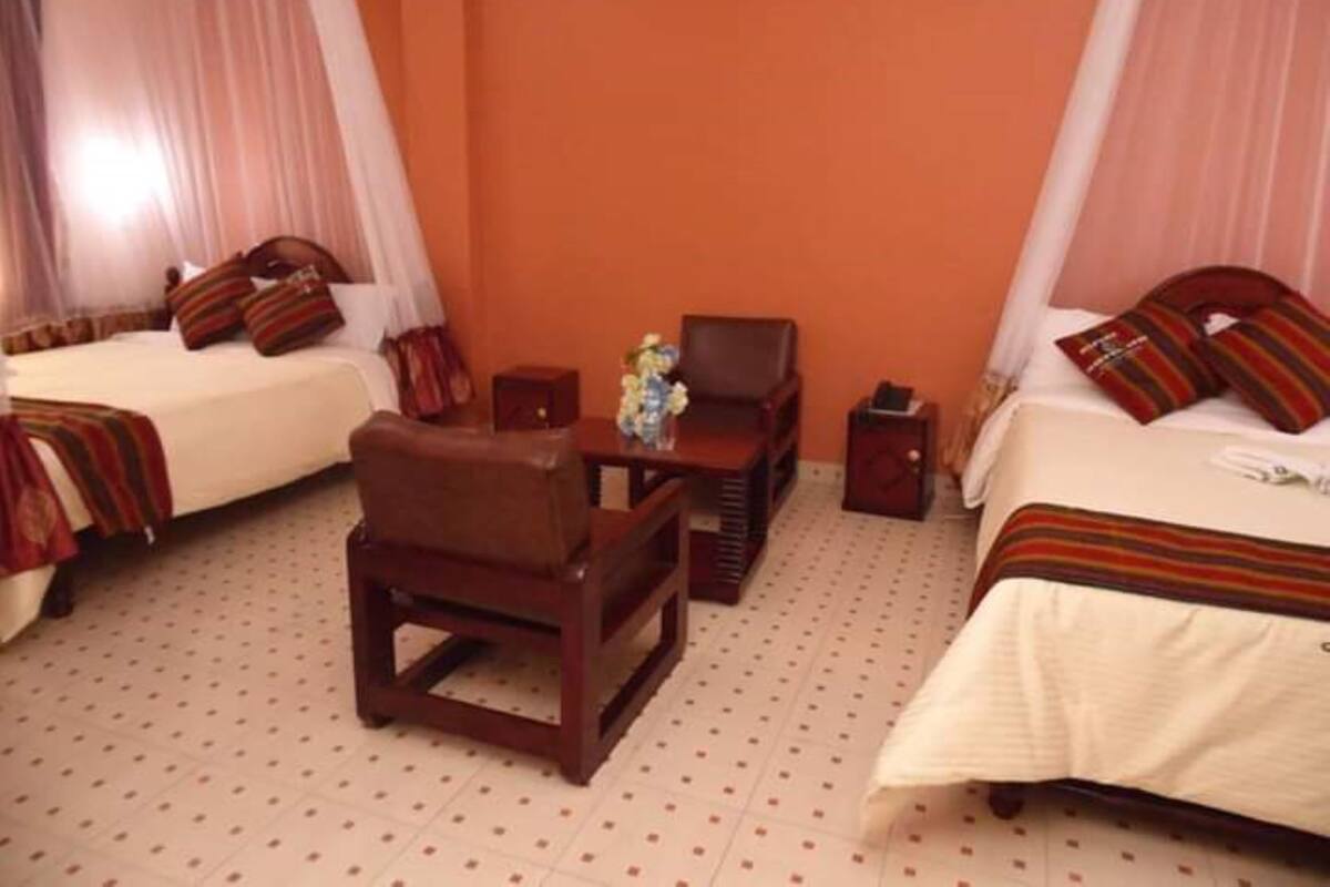 A hotel room with two beds, a small table, a chair, and a nightstand.