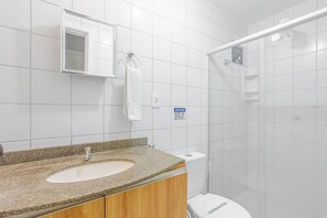 A modern bathroom with a granite countertop sink, a toilet, and a shower area. - BR01 Quarto de Sala Praia Porto Barra (Salvador)