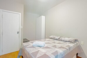 A bedroom with a bed, a door, and a mirror. - BR01 Quarto de Sala Praia Porto Barra (Salvador)