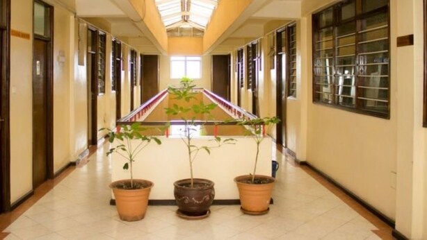 A long hallway with a central staircase, flanked by potted plants and glass doors on both sides. - Avenue Suites Hotel (Nakuru)