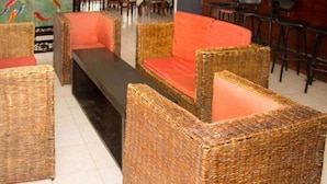 A seating area with wicker furniture and orange cushions. - Avenue Suites Hotel (Nakuru)