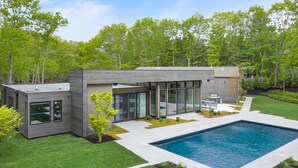 Una casa moderna con piscina, ventanas amplias y césped bien cuidado.