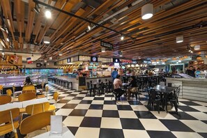 Una cafetería con suelo a cuadros, vigas de madera en el techo y varias zonas de comedor.