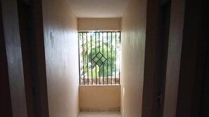 A narrow hallway with tiled flooring leading to a balcony with a metal gate. - Bellview Hotel (Thika)