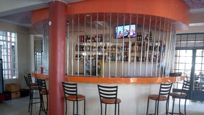 A bar area with a curved counter, metal bars, and several chairs. - Bellview Hotel (Thika)