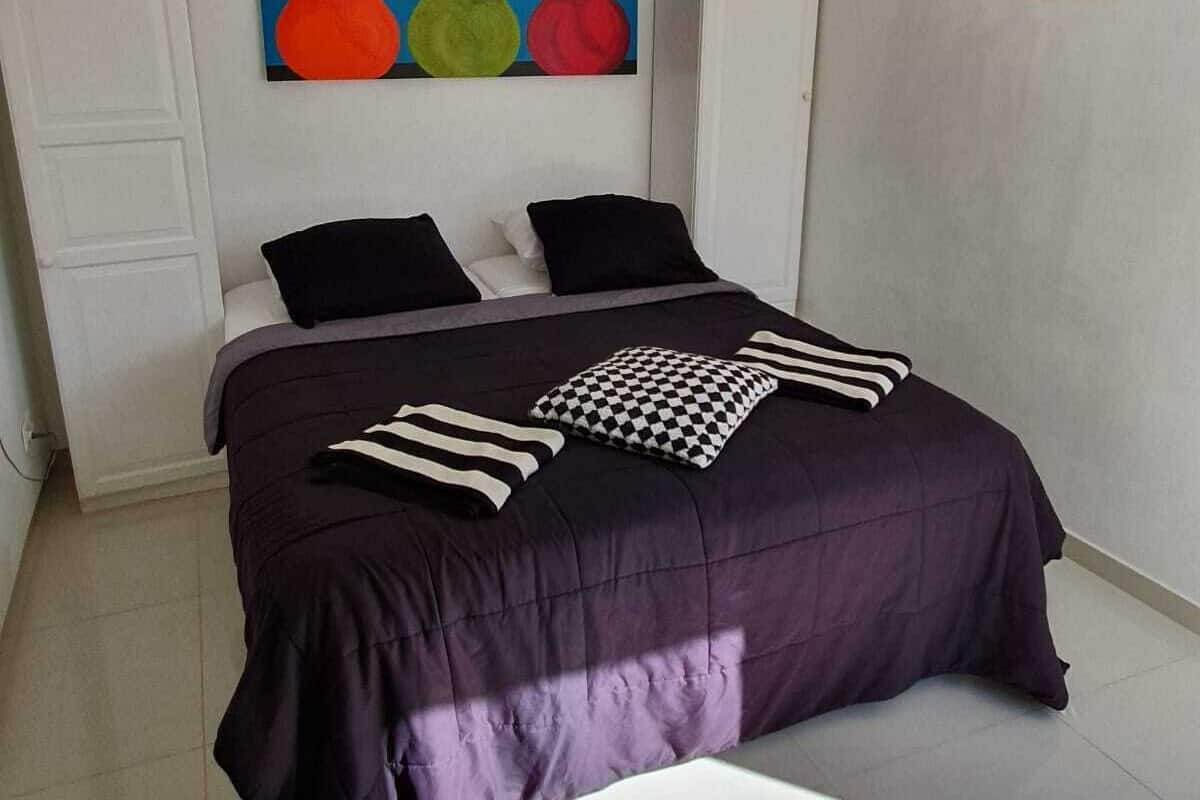 A bedroom with a bed, pillows, and two paintings on the wall.