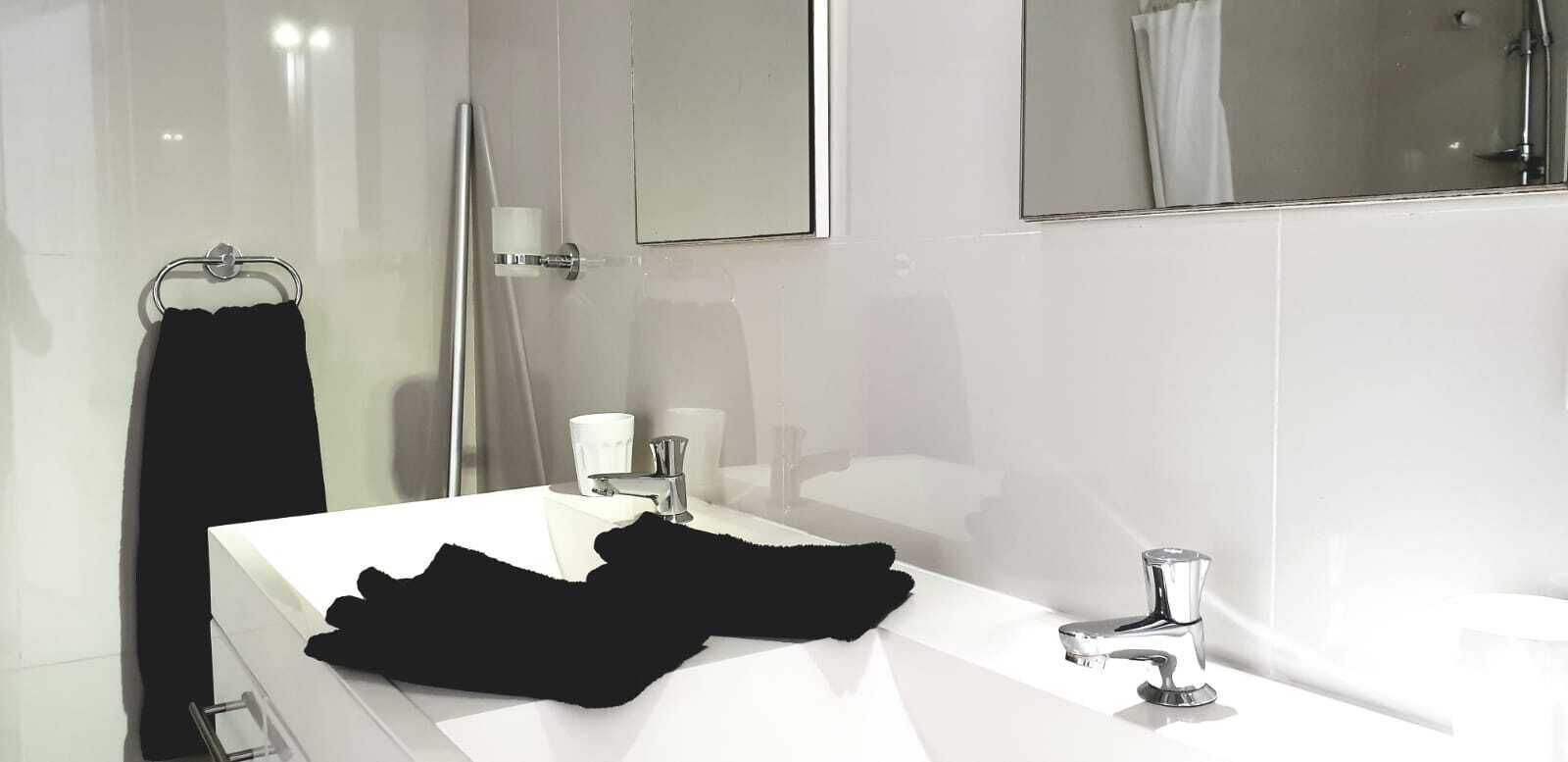 Un baño moderno con un lavabo blanco, un perchero para toallas y un espejo.