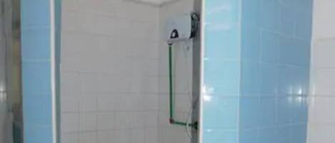 Un área de ducha pequeña y cerrada con azulejos azules y una puerta de vidrio.