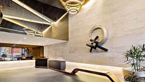 A modern lobby with a reception desk, seating area, and a large potted plant. - YARRA · YARRA Toorak Rd & Chapel St. Pool, Gym & Parking (South Yarra)