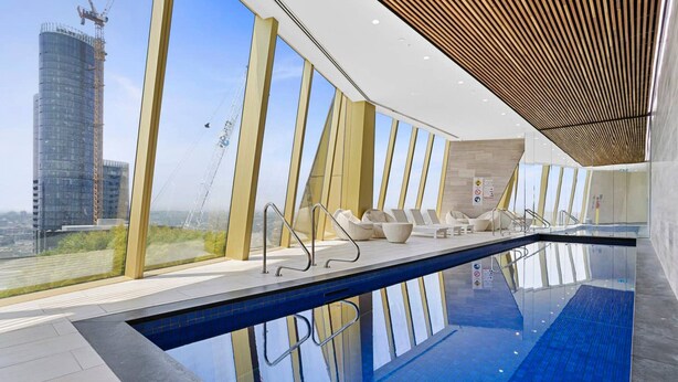 A modern indoor swimming pool with a clear view of a construction crane outside. - YARRA · YARRA Toorak Rd & Chapel St. Pool, Gym & Parking (South Yarra)