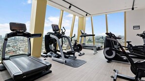 A gym with treadmills, ellipticals, and a stationary bike, featuring large windows with a city view. - YARRA · YARRA Toorak Rd & Chapel St. Pool, Gym & Parking (South Yarra)