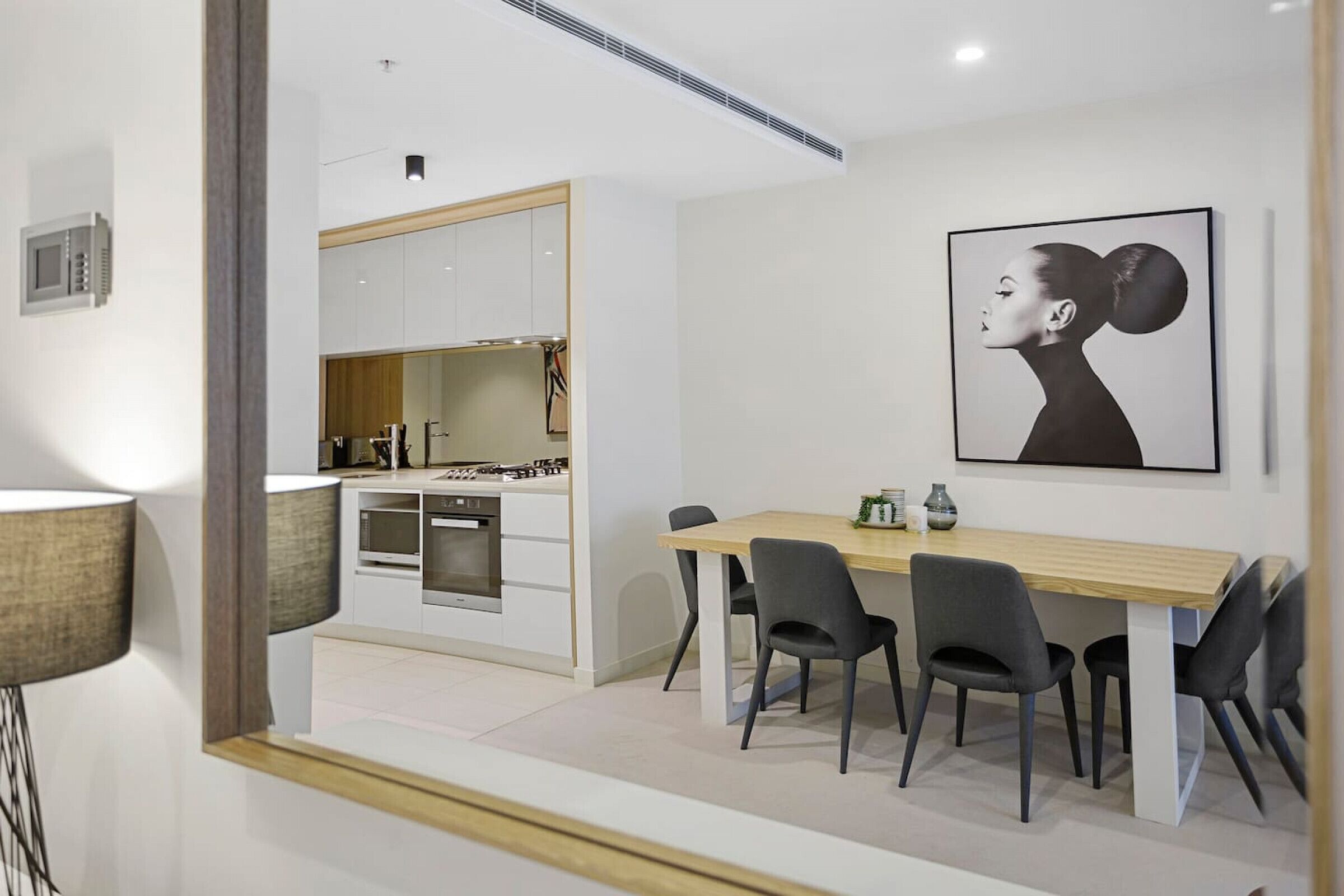 A modern kitchen with white cabinets, a wooden dining table, and four chairs.