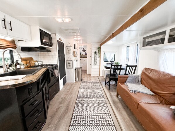 Compact kitchen with stainless steel sink, black stove, and wooden countertop.