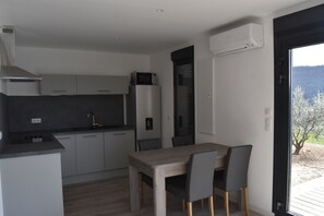 A modern kitchen with grey cabinets, a built-in microwave, and a dining area with a wooden table and chairs.