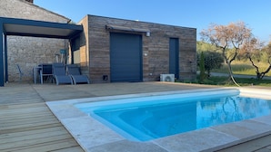 Ein modernes Haus mit Schwimmbad, überdachter Terrasse und Steinmauer.