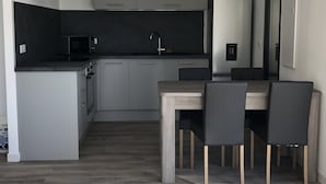 Eine moderne Küche mit grauen Schränken, einer schwarzen Arbeitsplatte und einem Edelstahl-Kühlschrank.
