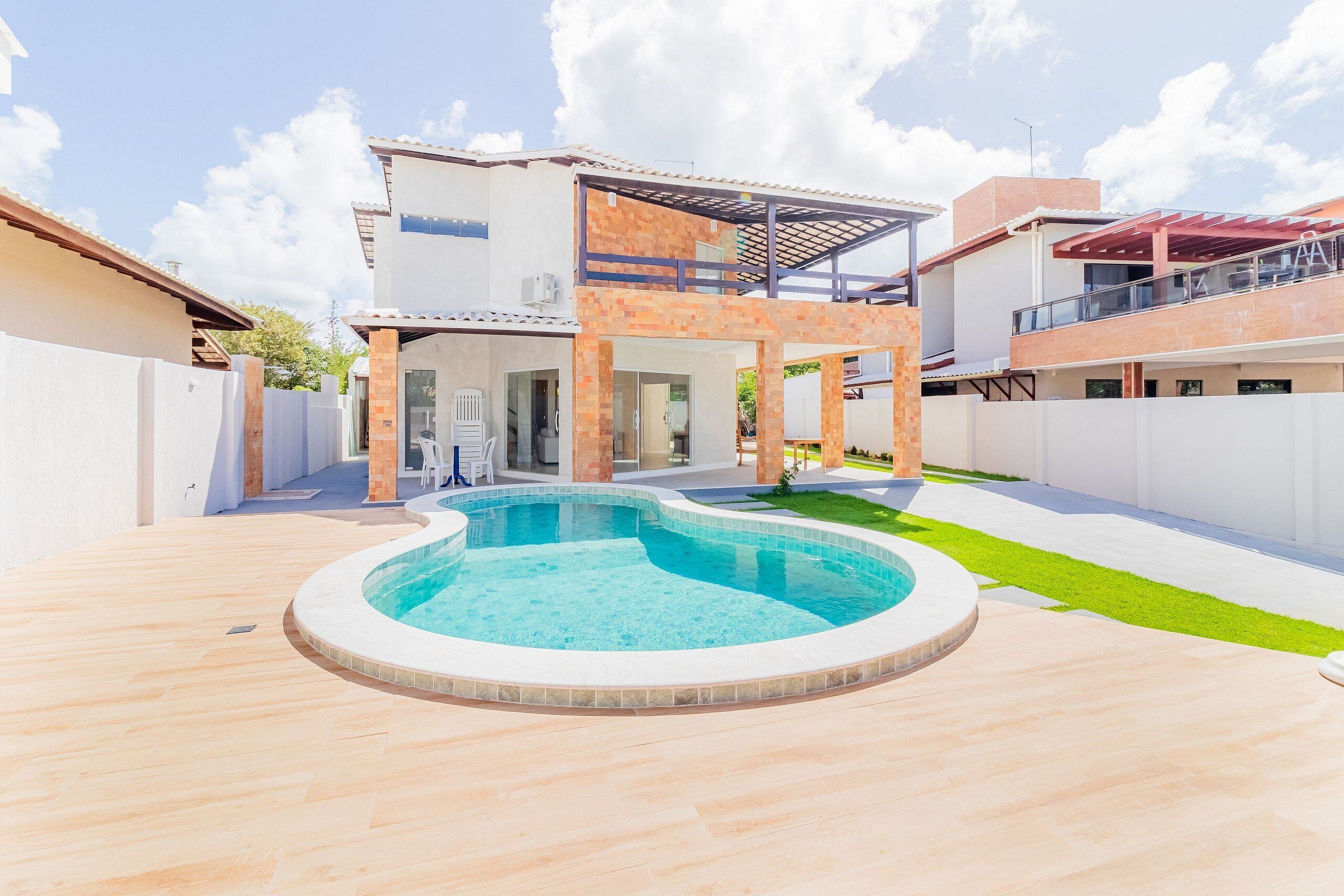 A modern house with a swimming pool, a covered patio, and a well-maintained lawn.