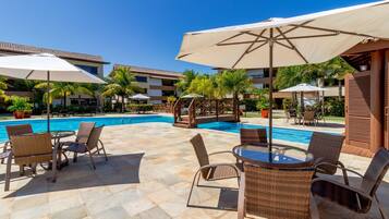 Una piscina al aire libre, sombrillas, sillones reclinables de piscina