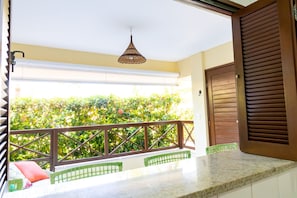 A balcony with a view of greenery, a hanging light fixture, and a wooden door. - GB11 Otimo Ap Genipabu Sum Residence (Camaçari)
