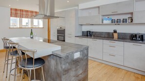 A modern kitchen with a central island, bar stools, a built-in oven, and a coffee station. - 3 bedroom accommodation in Woodhead, near Turriff (Woodhead, near Turriff)