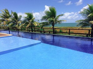 Piscina com vista para o oceano e palmeiras.