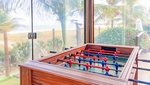 A foosball table with a view of palm trees and a beach. - IT70 Ótimo bangalô duplex à beira-mar (Camaçari)