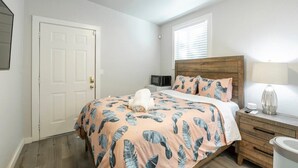 A bedroom with a bed, a wooden headboard, a bedside table with a lamp, and a white door. - @ Marbella Lane - MiniGuest House | DTWN SJ | Parking (San Jose)