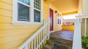 A yellow house with a red door, white railings, and stone steps leading to the entrance. - Marbella Lane - 3BR UpprLvl | DTWN SJ | Ldry + P (San Jose)