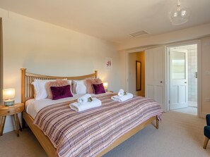 A bedroom with a wooden bed, two bedside tables, a mirror, and a door leading to a bathroom.