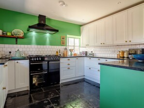 A kitchen with white cabinets, a black stove, and a green wall.