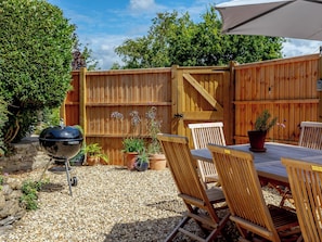 A wooden deck with a grill, potted plants, and outdoor furniture.