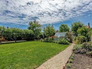 A backyard with a lawn, a gravel path, and a greenhouse.