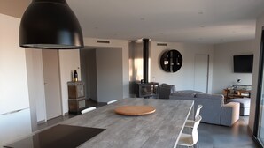 A modern kitchen with a central island, a built-in stove, and a large black pendant light. - Magnificent villa with private pool (Mirepeisset)