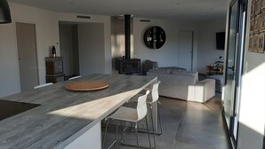A modern kitchen with a central island, a built-in stove, and a dining area with bar stools. - Magnificent villa with private pool (Mirepeisset)
