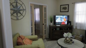 Uma sala de estar com televisão, decoração em estrela, quadro e planta.
