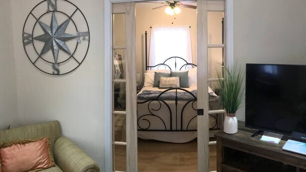 Quarto com uma cama, uma TV e uma bússola decorativa na parede.