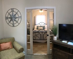A bedroom with a bed, a TV, and a decorative compass on the wall. - The Cottage on Shurley (Rock Hill)