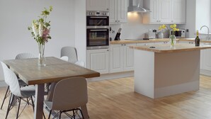 Una cucina moderna con mobili bianchi, un tavolo da pranzo in legno e un'isola centrale.