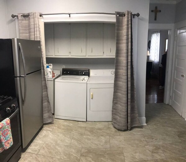 A compact kitchen with a refrigerator, stove, washing machine, and cabinets.