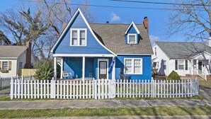 A two-story house with a blue exterior and a white picket fence.